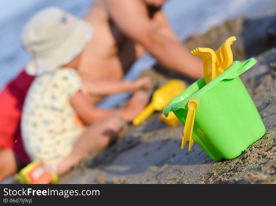 Father and son playng on sandy beach toys closer to viewer. Father and son playng on sandy beach toys closer to viewer