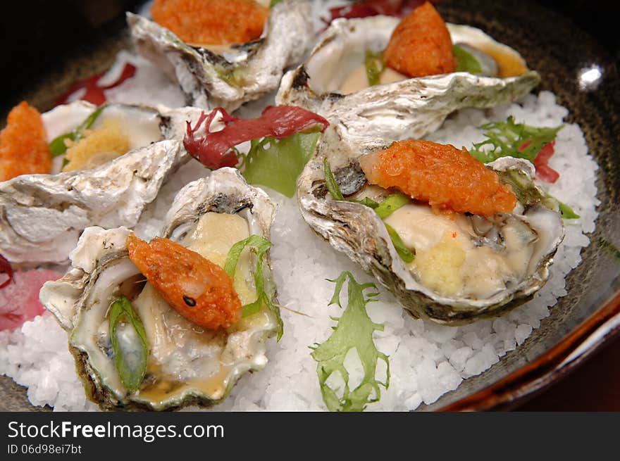 Beautifully plated raw oysters on the half shell over ice. Each oyster also has a tempura vegetable on top. Beautifully plated raw oysters on the half shell over ice. Each oyster also has a tempura vegetable on top.