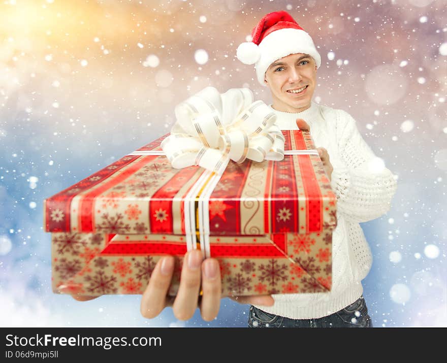 Portrait of a handsome young man in Santa Claus hat holding a big red gift box. Portrait of a handsome young man in Santa Claus hat holding a big red gift box