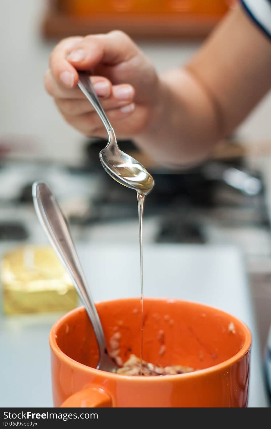 Woman hand adding honey in banana puree. Woman hand adding honey in banana puree