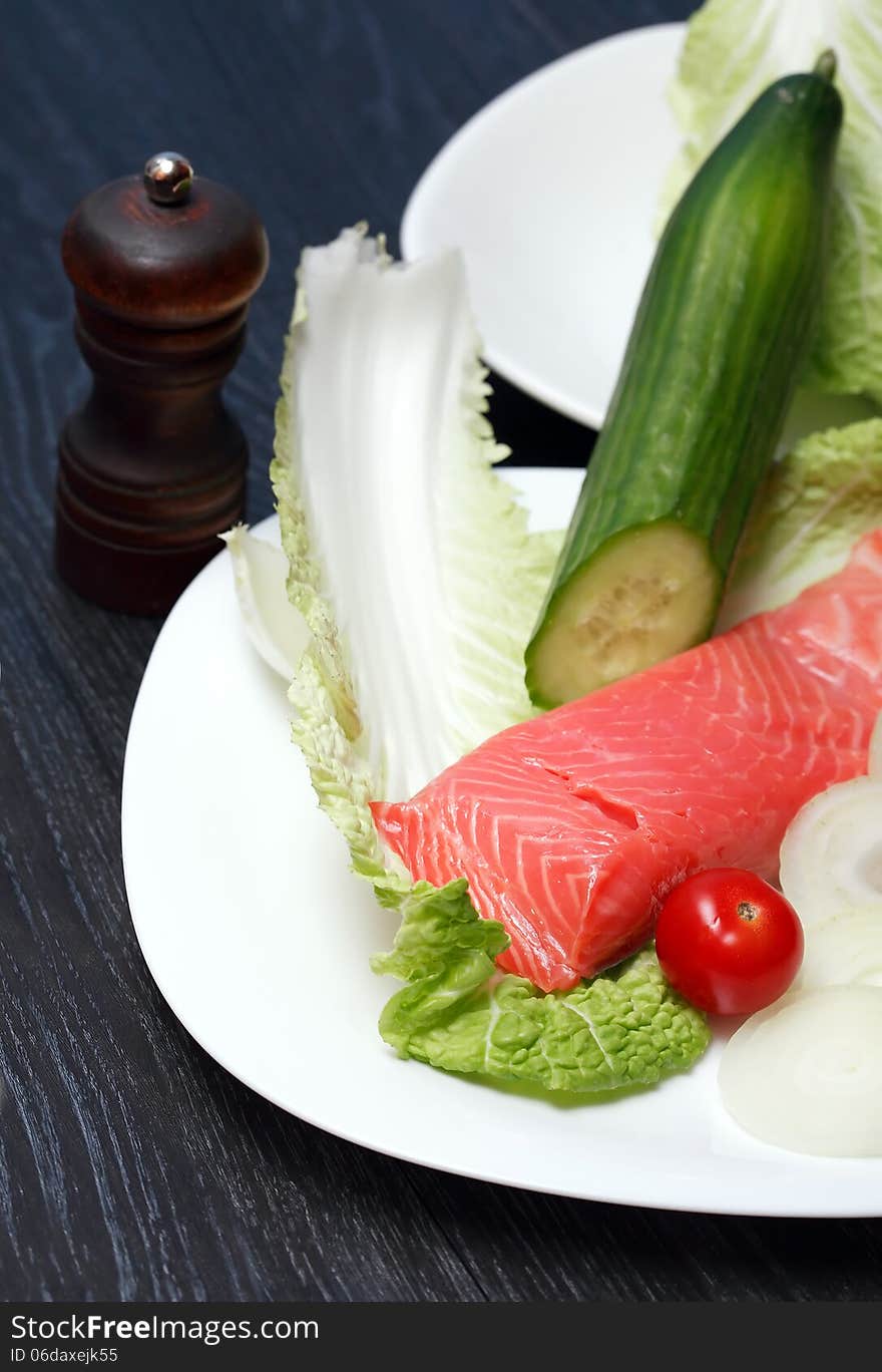 Closeup of filleted salmon on plate near various vegetables. Closeup of filleted salmon on plate near various vegetables