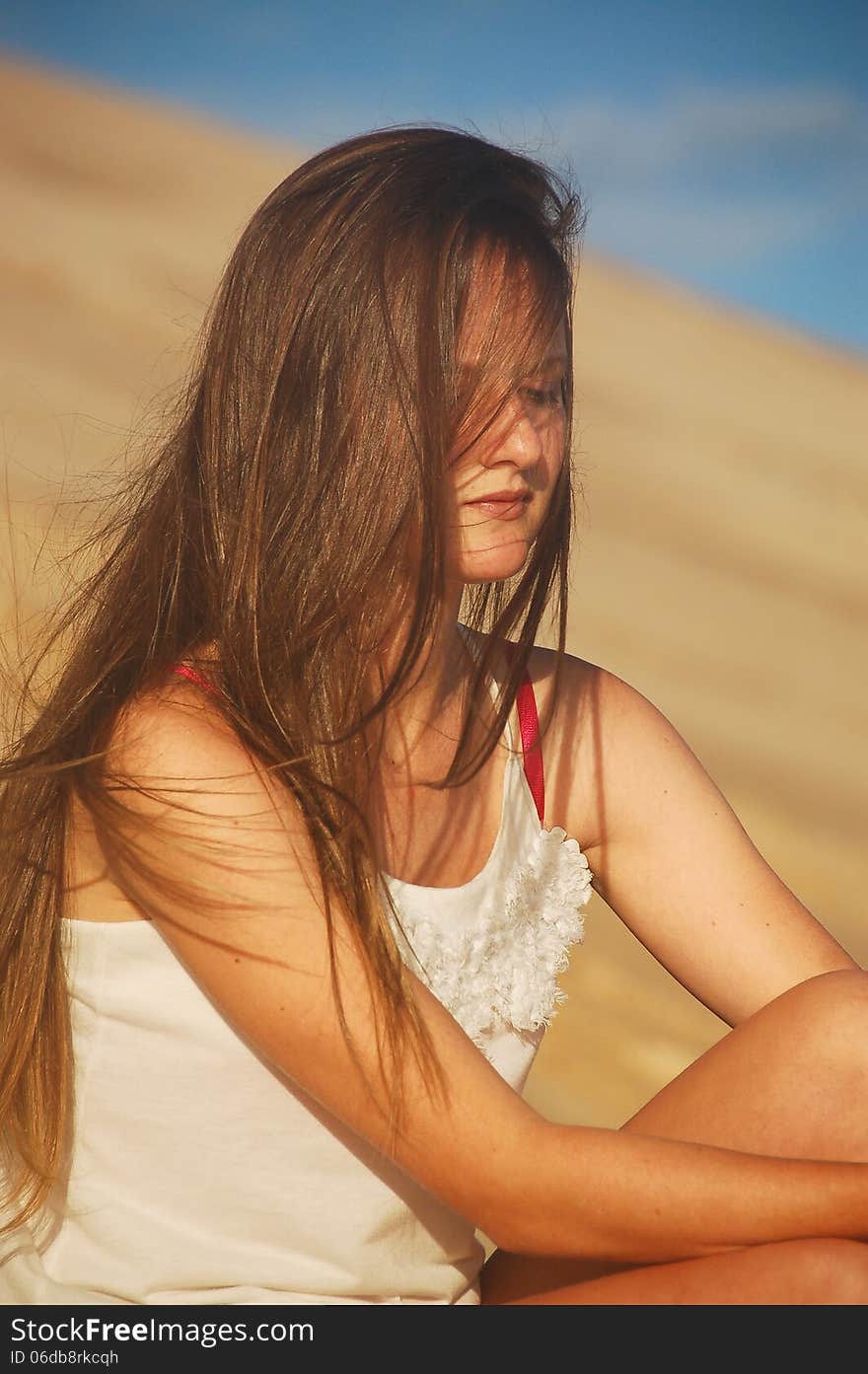 A shy or depressed looking teenager allows a summer sea breeze to blow her long hair around her face . A shy or depressed looking teenager allows a summer sea breeze to blow her long hair around her face .