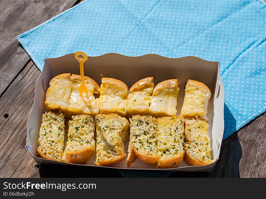 Fresh-baked garlic bread with herbs, on white bread tray in market