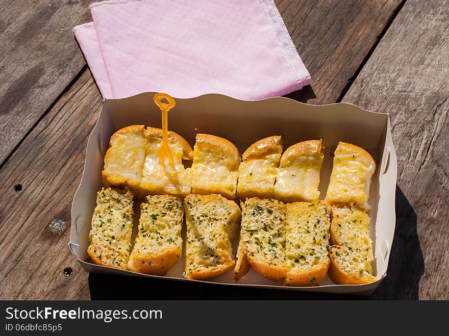 Fresh-baked garlic bread with herbs, on white bread tray in market