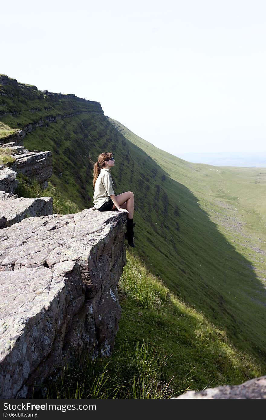 GIRL SITTING ON THE TOP OF A CLIFF