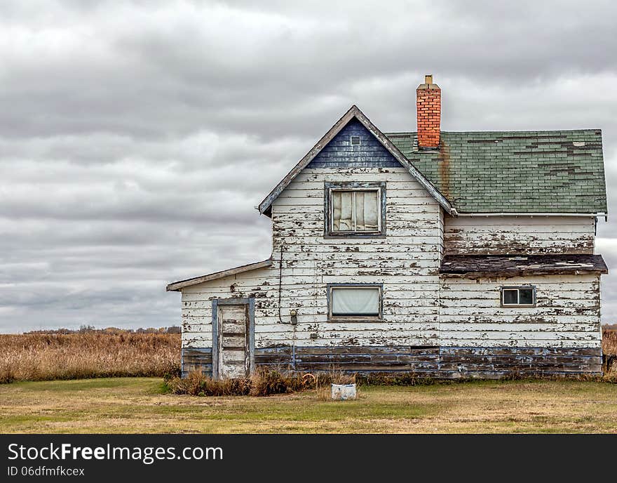 Old abandoned blue and white house.the paint is peeling off the wood siding. Old abandoned blue and white house.the paint is peeling off the wood siding