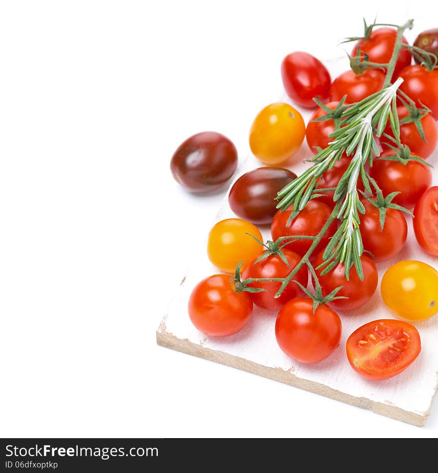 Colorful cherry tomatoes and rosemary on a white wooden board, isolated on white