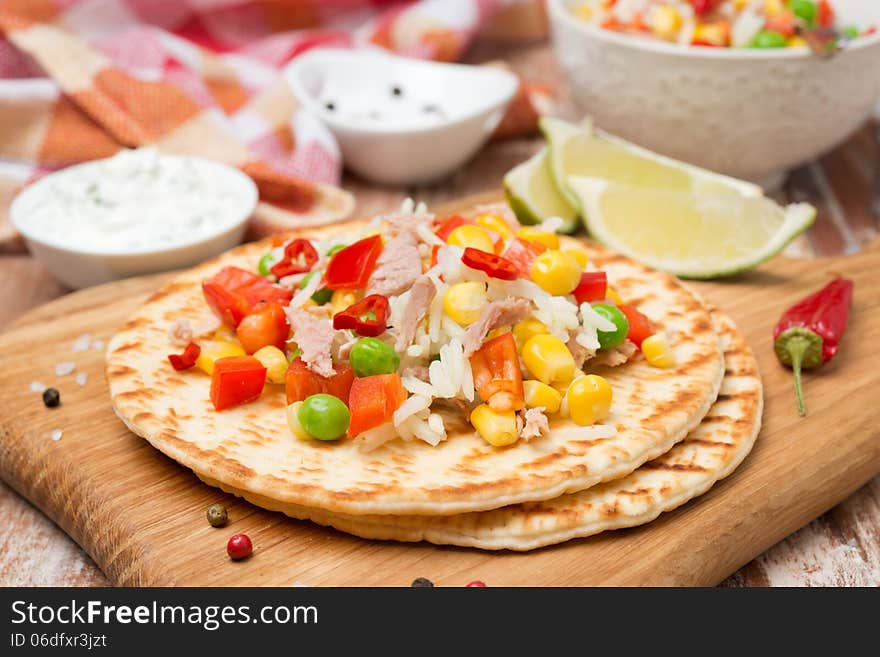 Colorful vegetable salad with tuna and cream sauce on a wheat tortilla, close-up. Colorful vegetable salad with tuna and cream sauce on a wheat tortilla, close-up