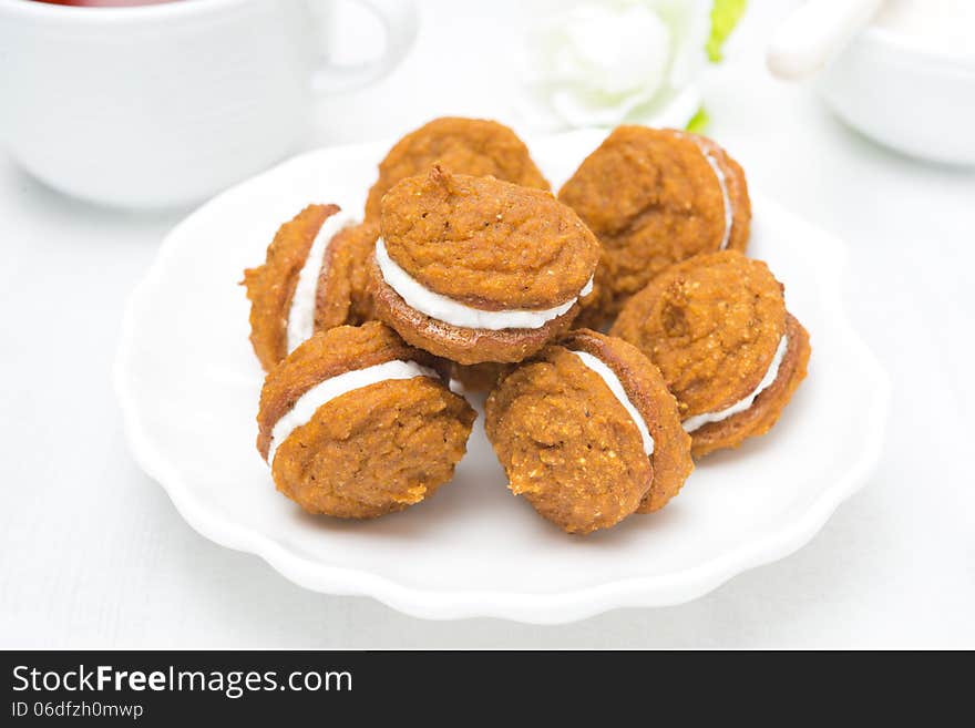 Pumpkin Cookies With Cream Filling On A White Plate