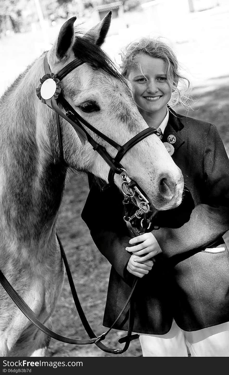 A sweet grey pony with a rosette and a young smiling blonde girl. A sweet grey pony with a rosette and a young smiling blonde girl.