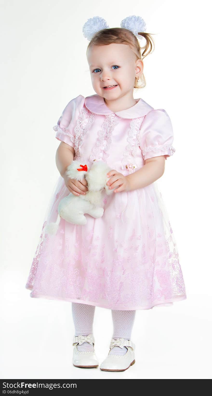 Little girl standing in full growth with toy and smiling