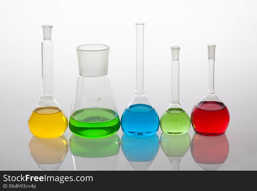 Laboratory glassware with liquids of different colors, isolated on white background