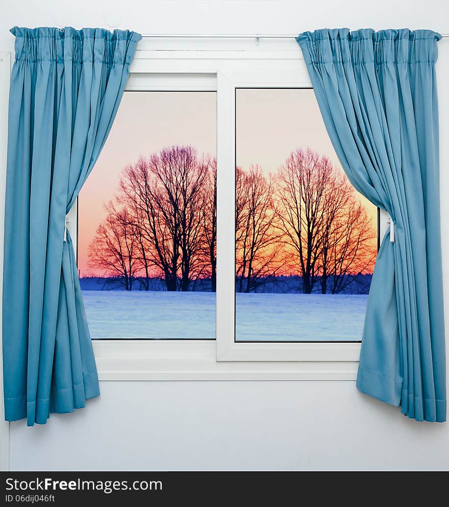 View from the window with the curtains of the sunset over the snow. View from the window with the curtains of the sunset over the snow