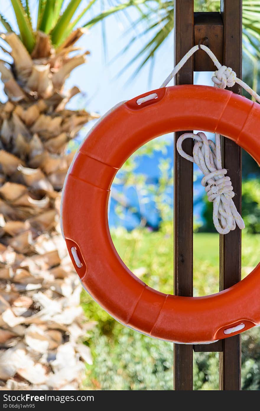 Orange life buoy with rope hanging around the pool