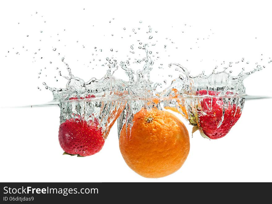 Orange and strawberries falling into the water. Orange and strawberries falling into the water