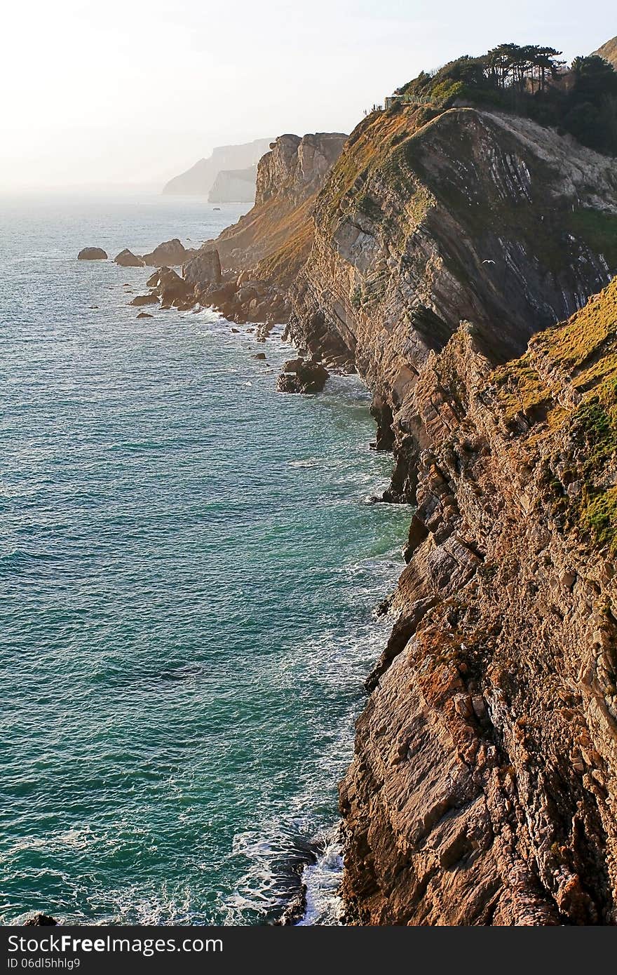 The Jurassic Coast showing rock strata, near West Lulworth, Purbeck, Dorset The Jurassic Coast is a World Heritage Site on the south coast of England. It reaches from Devon in the west to Old Harry Rocks near Swanage, Dorset, to the East. The Jurassic Coast showing rock strata, near West Lulworth, Purbeck, Dorset The Jurassic Coast is a World Heritage Site on the south coast of England. It reaches from Devon in the west to Old Harry Rocks near Swanage, Dorset, to the East