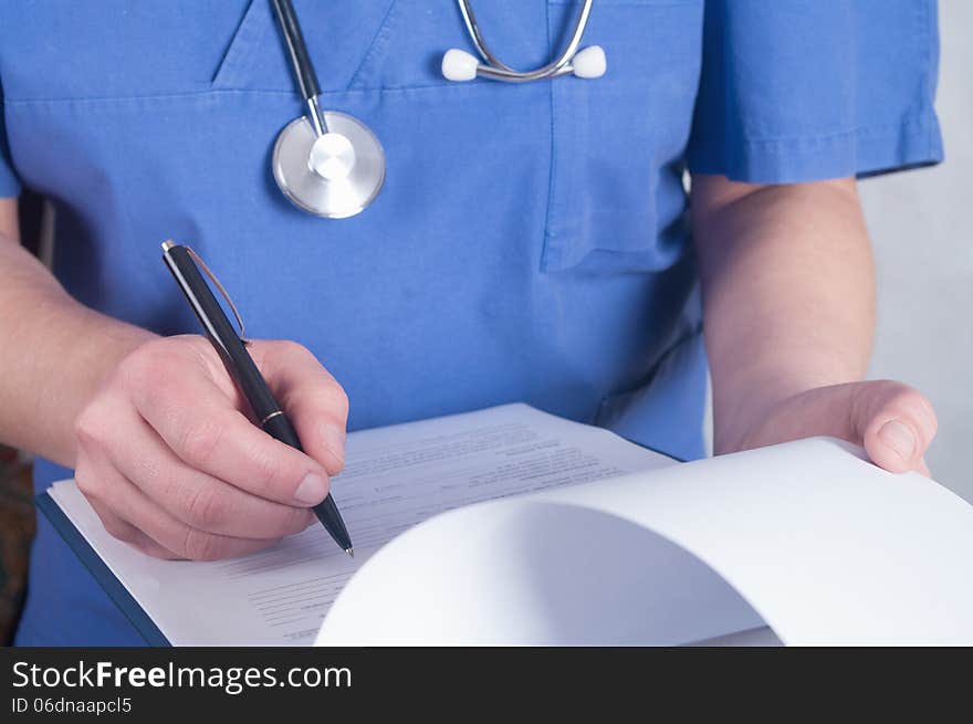 Hand of doctor with pen writing on prescription blank