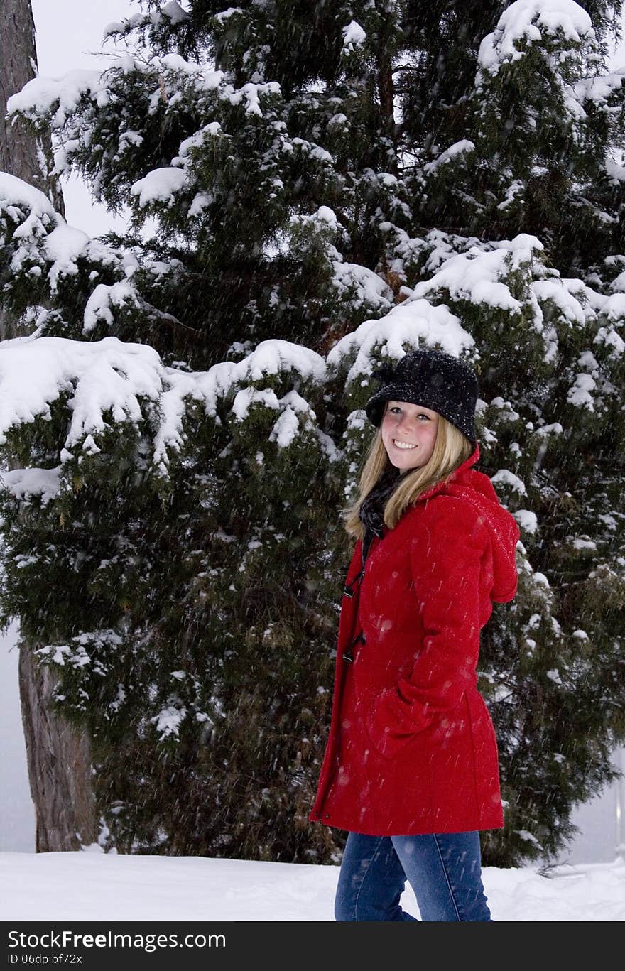 Blonde female in red coat and black hat in the middle of a snow storm. Blonde female in red coat and black hat in the middle of a snow storm.