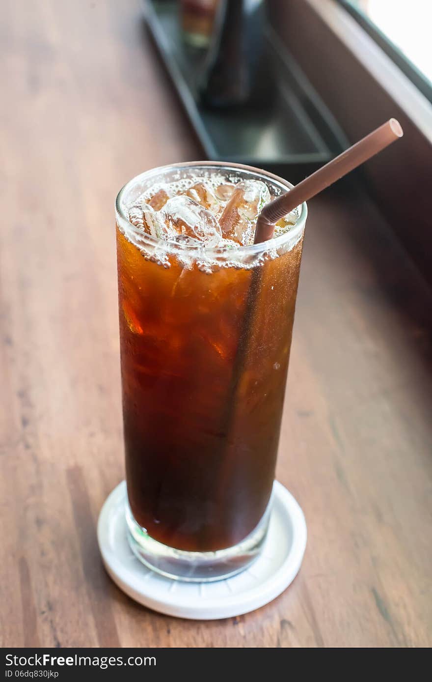 Iced black coffee on the wooden table in coffee cafe.