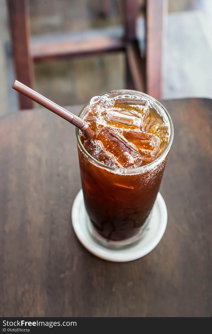 Iced black coffee on the wooden table in coffee cafe.