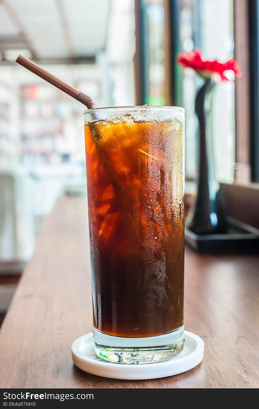 Iced black coffee on the wooden table in coffee cafe.