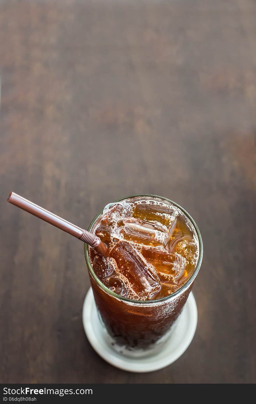 Iced black coffee on the wooden table in coffee cafe.