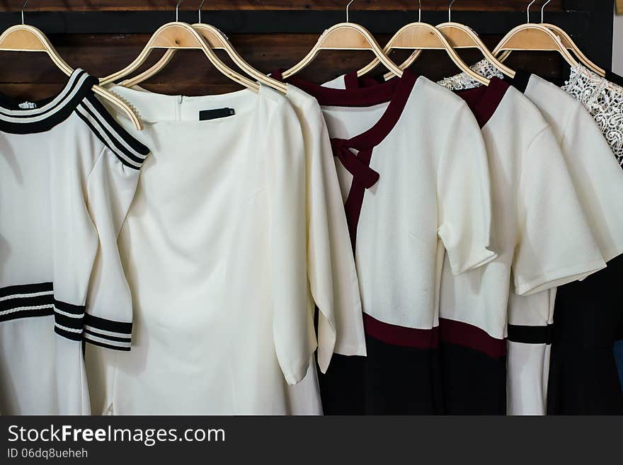 Many white blouses on hangers in the dressing room.