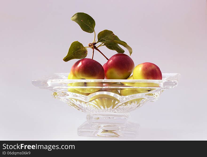 Crabapples in a glass bowl on a white background.