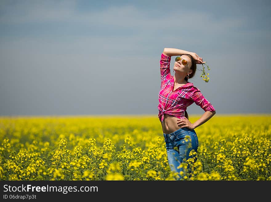 Young beautiful woman in flowering field in summer. Outdoors