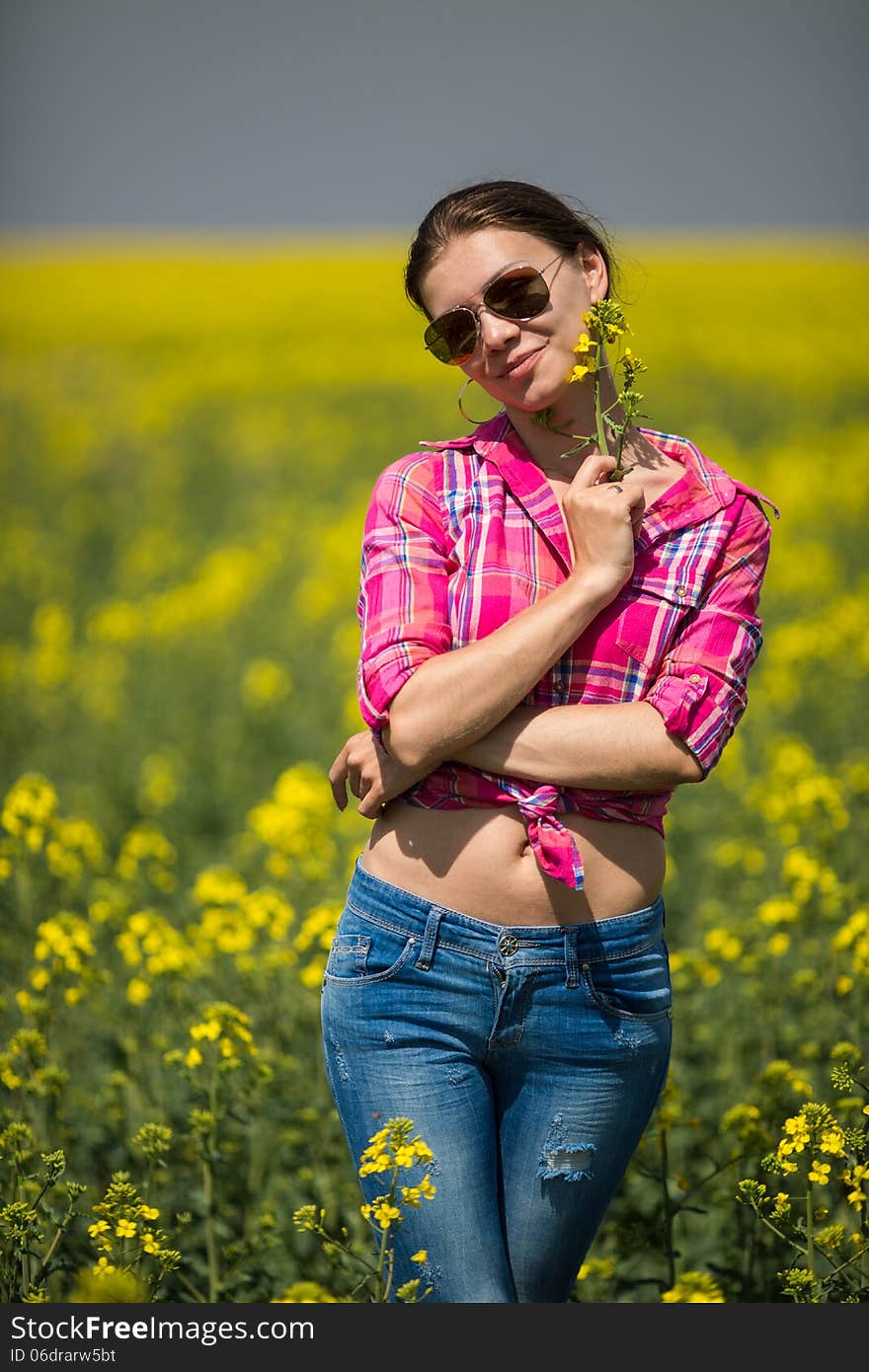 Young beautiful woman in flowering field in summer. Outdoors