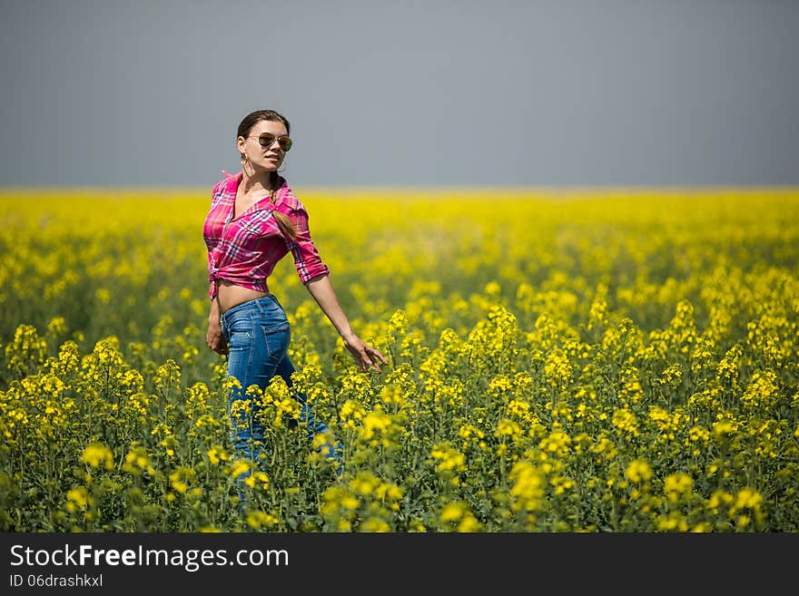 Young beautiful woman in flowering field in summer. Outdoors