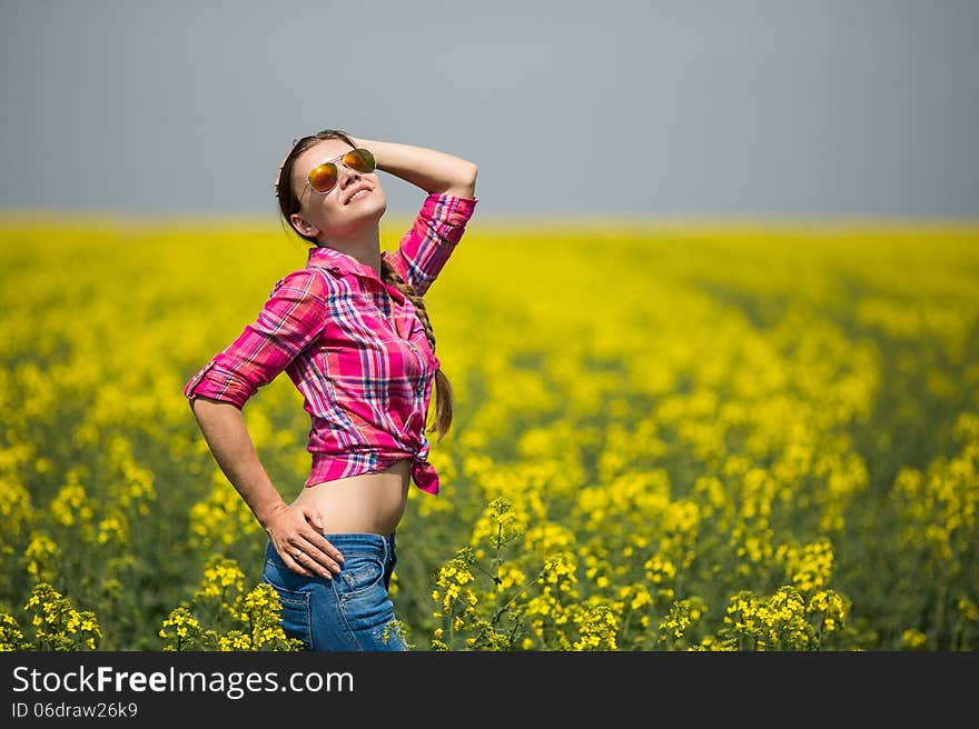 Young beautiful woman in flowering field in summer. Outdoors