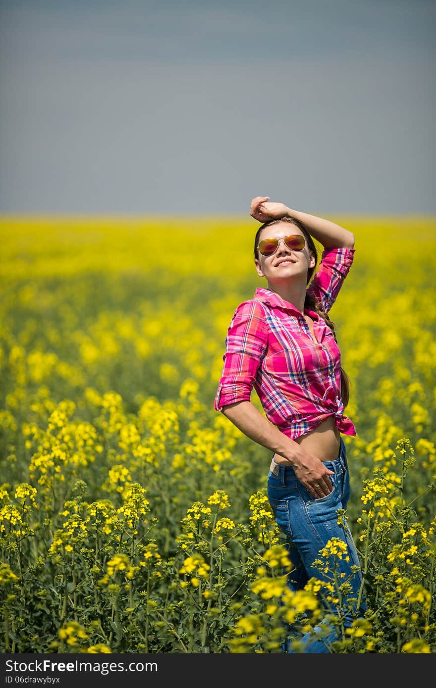 Young beautiful woman in flowering field in summer. Outdoors