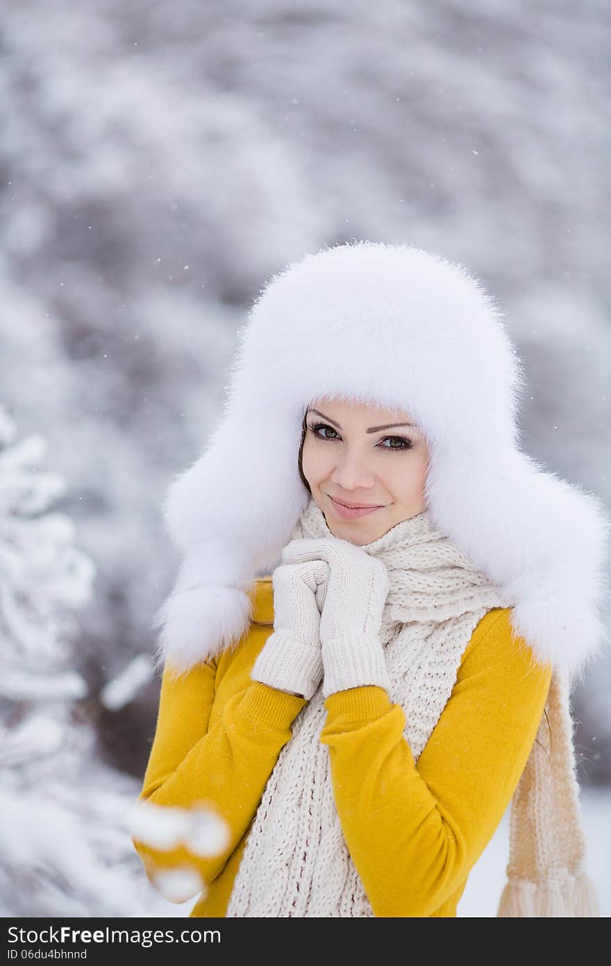 Winter portrait of beautiful smiling woman with snowflakes in white furs