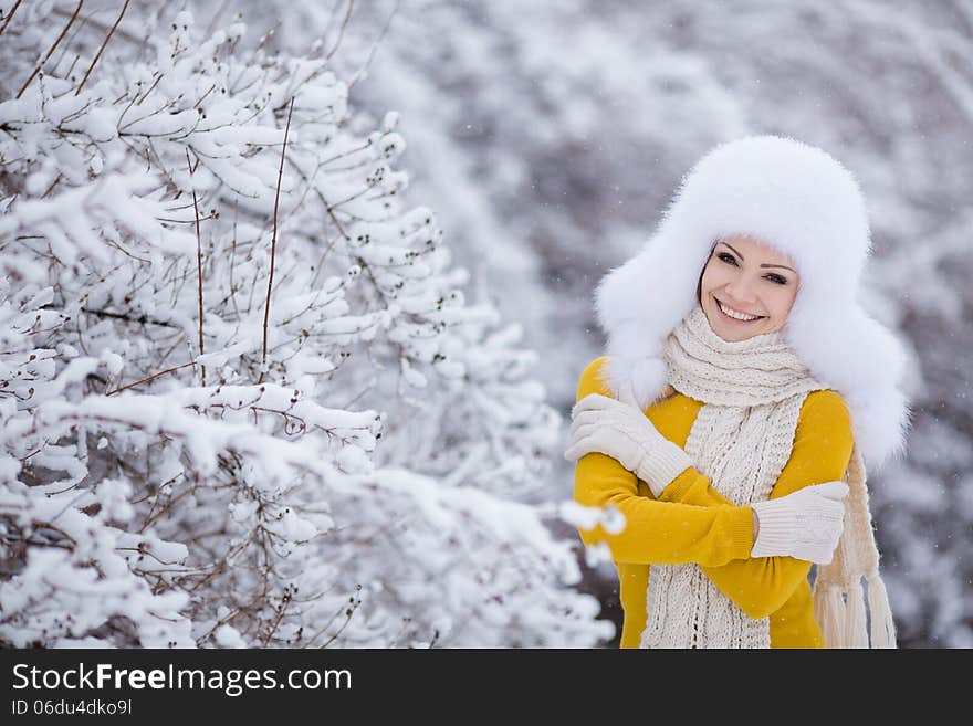 Winter portrait of beautiful smiling woman with snowflakes in white furs