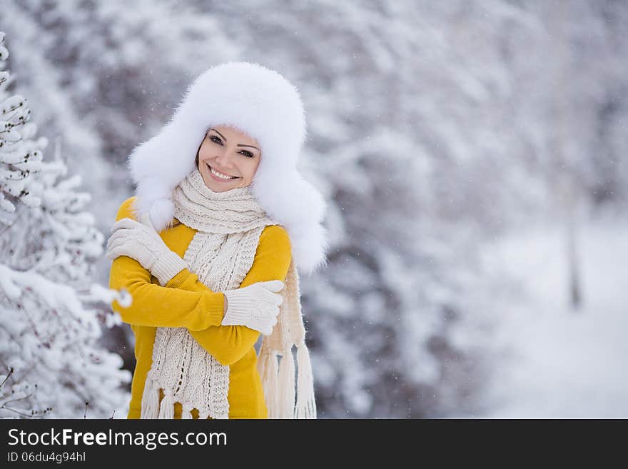 Winter portrait of beautiful smiling woman with snowflakes in white furs