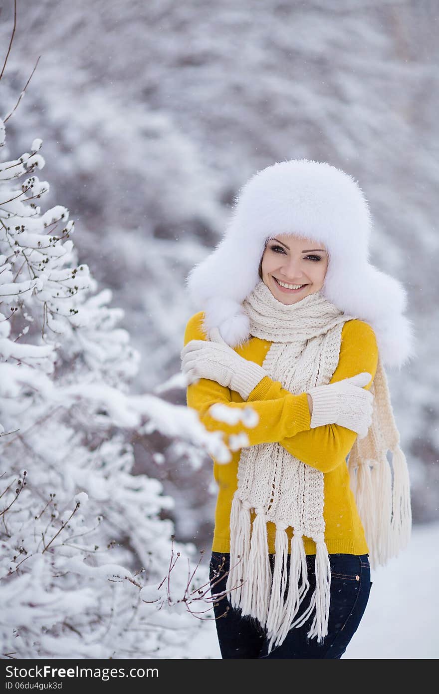 Winter portrait of beautiful smiling woman with snowflakes in white furs