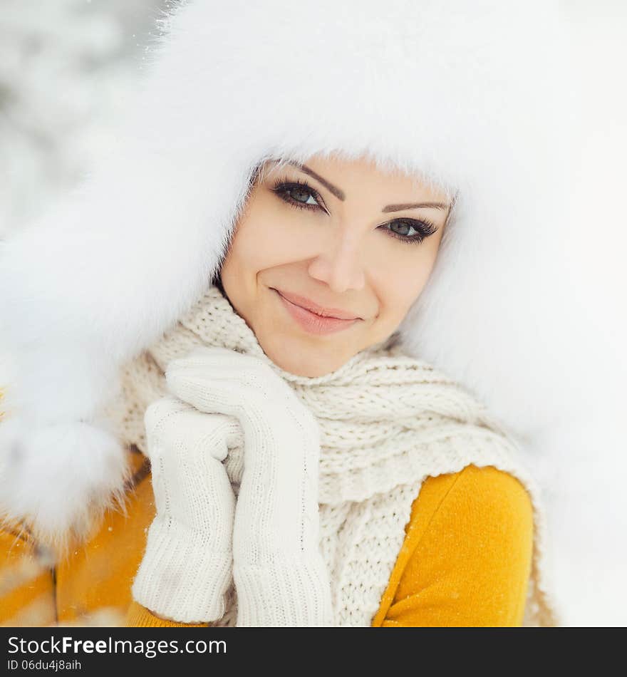 Winter portrait of beautiful smiling woman with snowflakes in white furs