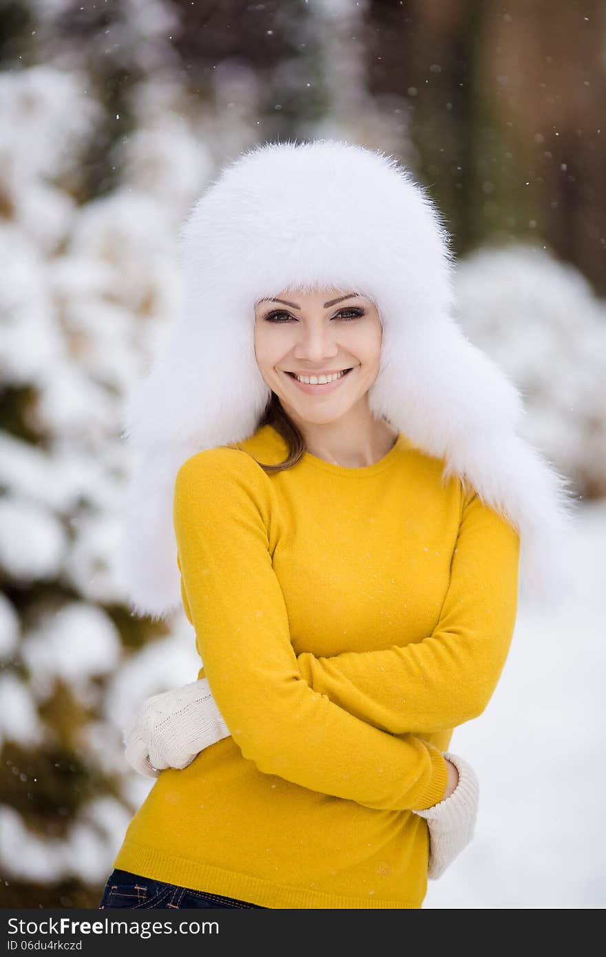 Winter portrait of beautiful smiling woman with snowflakes in white furs