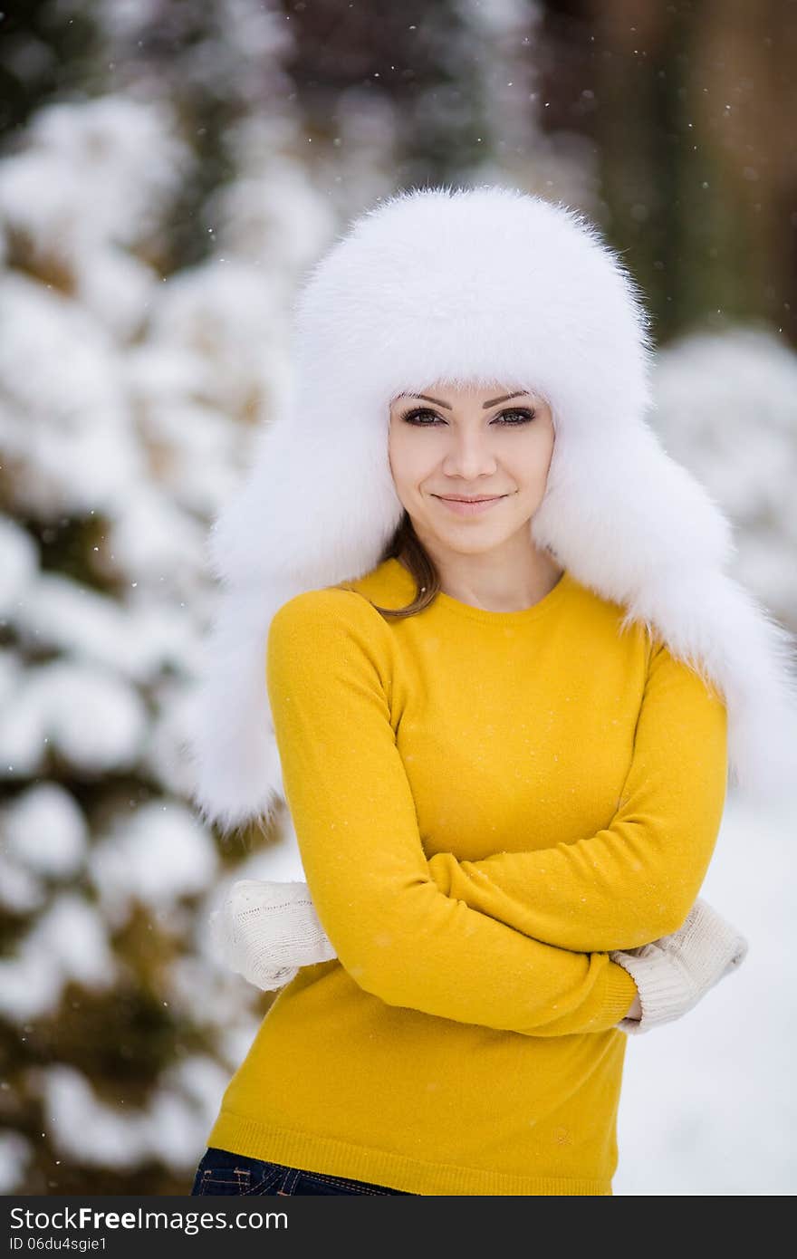 Winter portrait of beautiful smiling woman with snowflakes in white furs