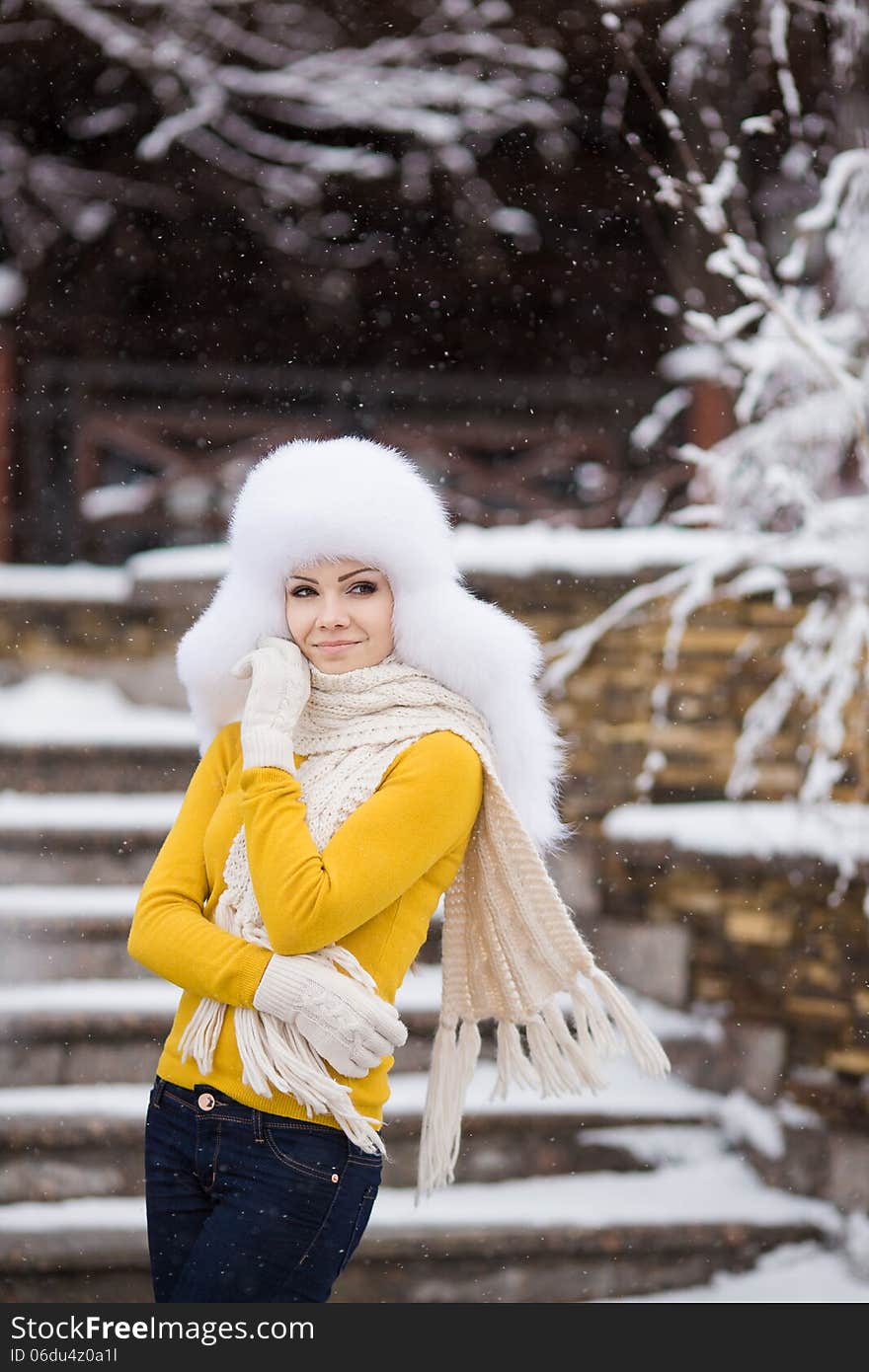 Winter portrait of beautiful smiling woman with snowflakes in white furs