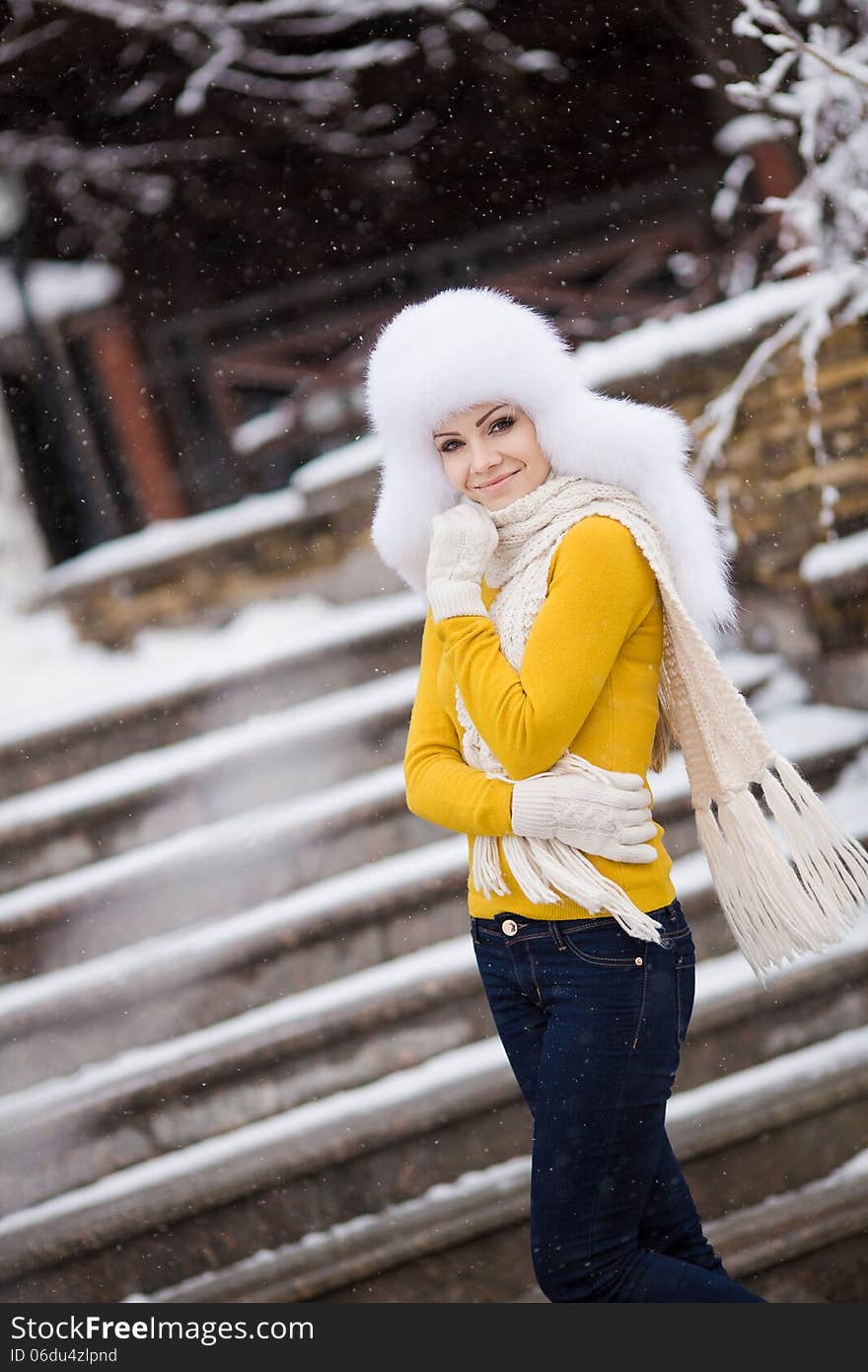 Winter portrait of beautiful smiling woman with snowflakes in white furs