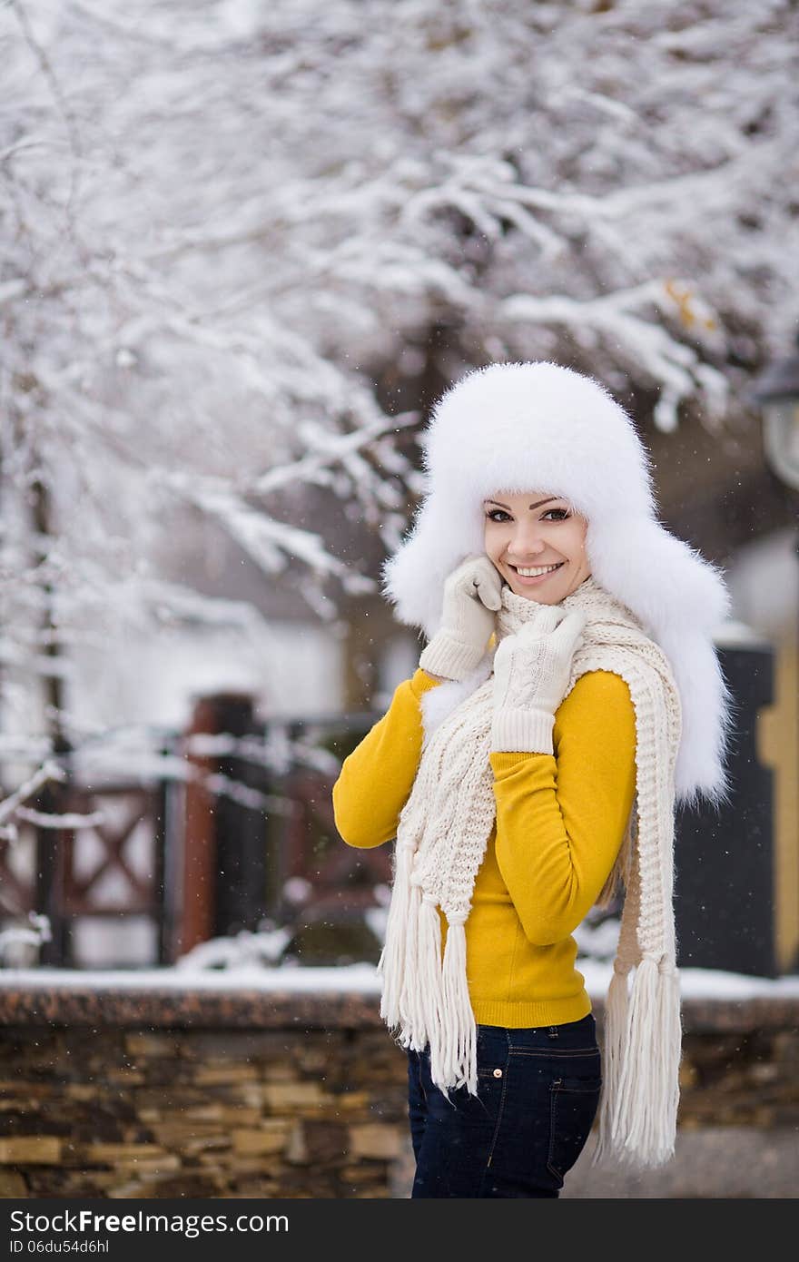 Winter portrait of beautiful smiling woman with snowflakes in white furs