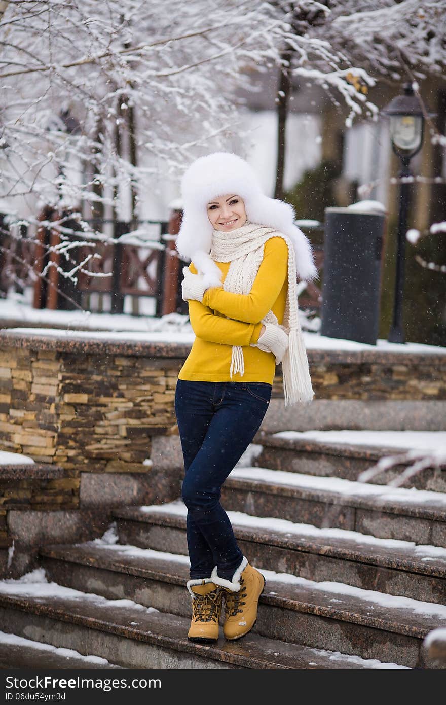 Winter portrait of beautiful smiling woman with snowflakes in white furs