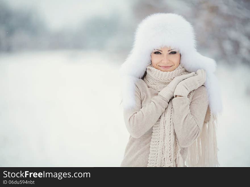 Winter portrait of beautiful smiling woman with snowflakes in white furs