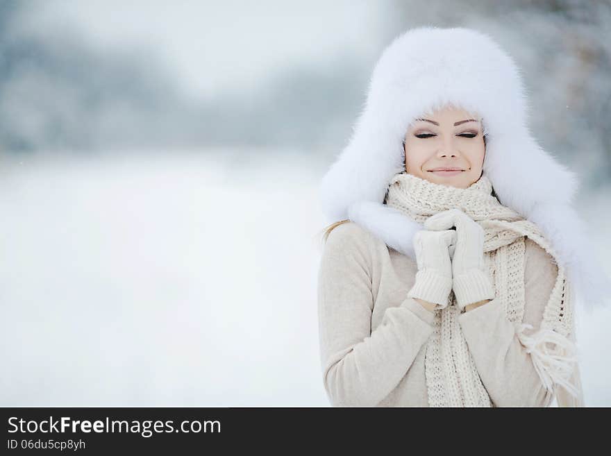 Winter portrait of beautiful smiling woman with snowflakes in white furs