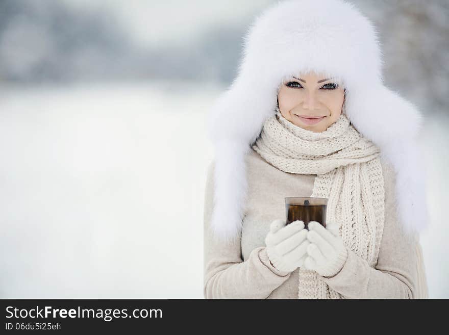 Winter portrait of beautiful smiling woman with snowflakes in white furs