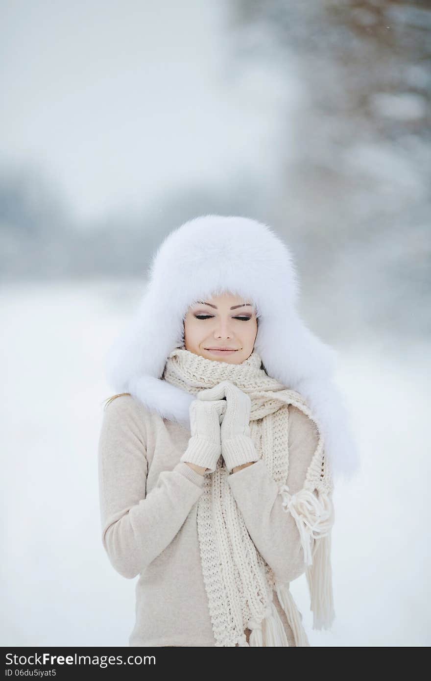 Winter portrait of beautiful smiling woman with snowflakes in white furs