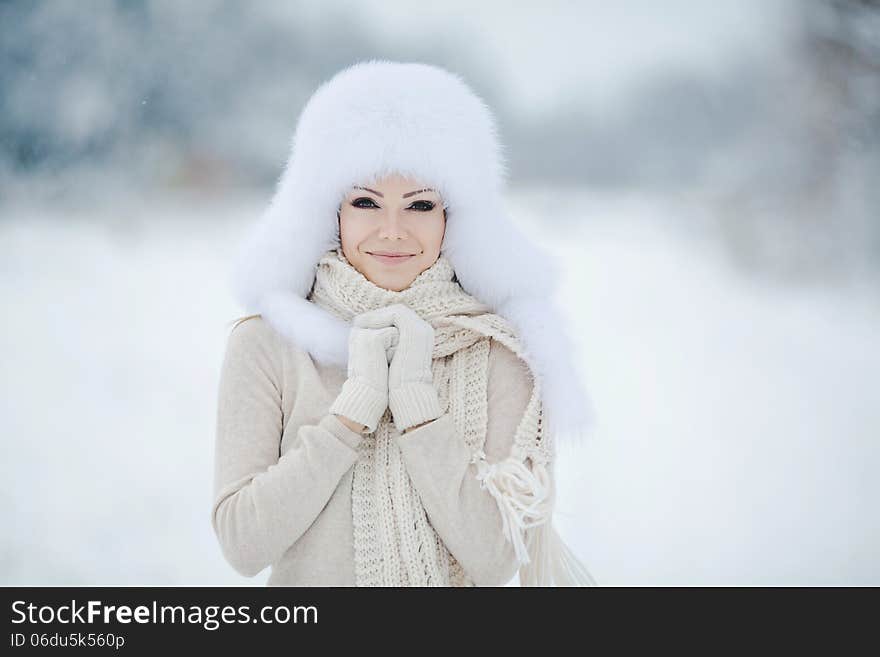 Winter portrait of beautiful smiling woman with snowflakes in white furs