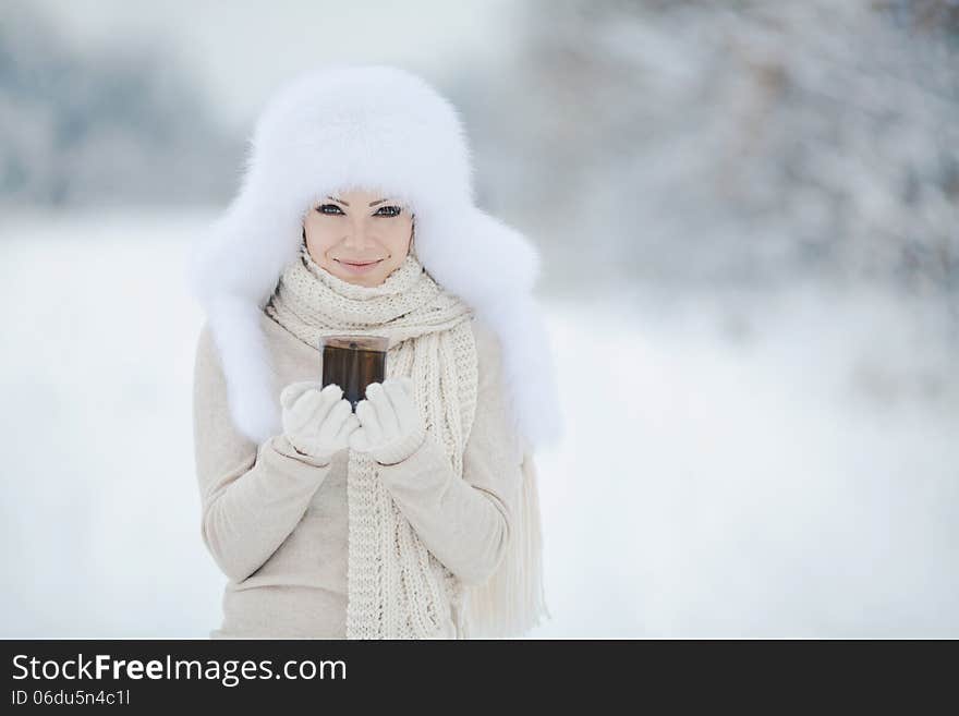 Winter portrait of beautiful smiling woman with snowflakes in white furs